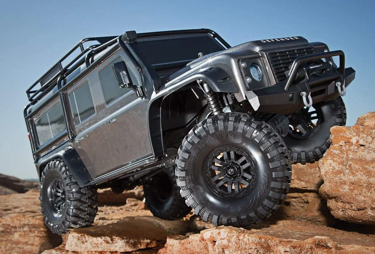 Gray Traxxas TRX-4 RC crawler with a Land Rover Defender body climbing over rocks