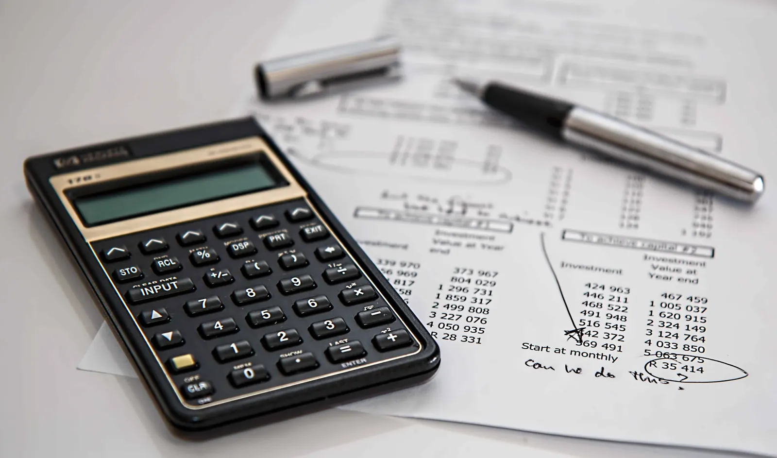 Calculator, pen and a sheet of handwritten budget figures