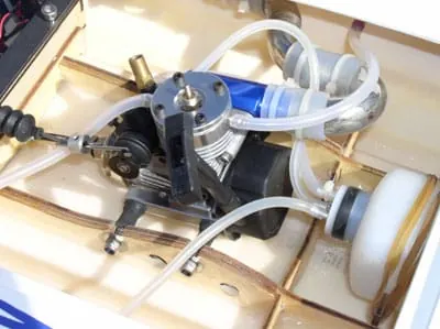 Nitro engine mounted inside an RC boat hull with its fuel and cooling lines