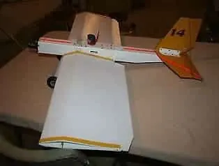 Homemade white RC plane with a yellow tail marked 14, sitting on a workbench