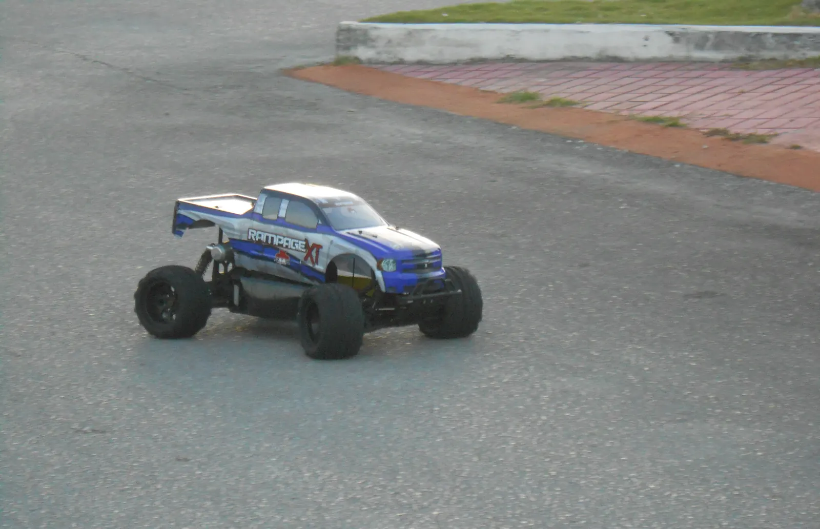 Monster truck RC azul rodando sobre asfalto