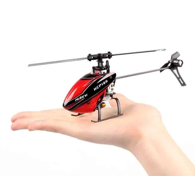 Red mini RC helicopter with a single main rotor resting on the palm of a hand