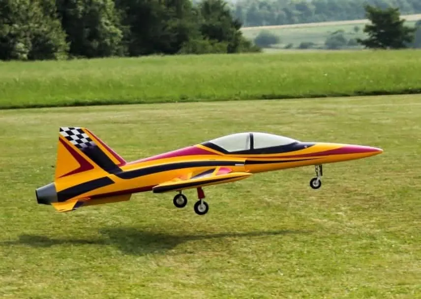 Yellow and red RC jet turbine plane taxiing on the grass