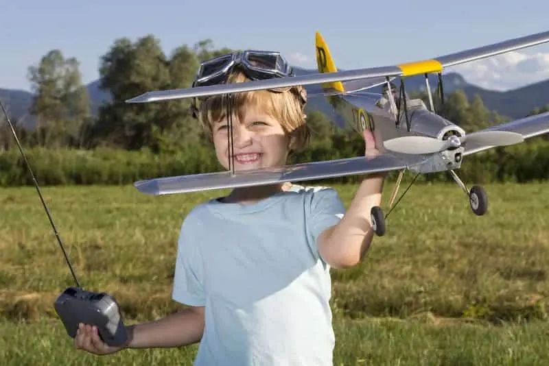 Child holding an RC plane in a field