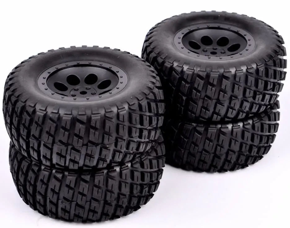 Four knobby off-road RC tires on black wheels, stacked in pairs