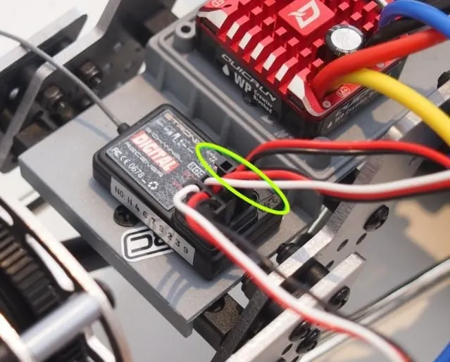RC car receiver mounted on the chassis next to a red waterproof ESC, with servo leads plugged in