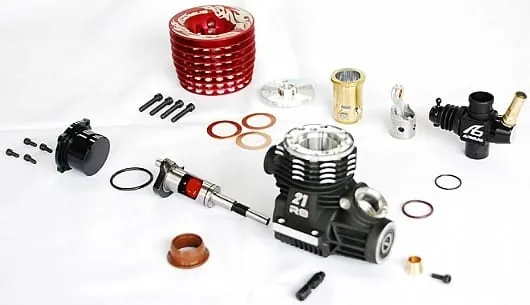 Disassembled nitro RC car engine: red cylinder head, carburetor, piston and sleeve
