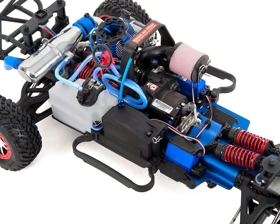 Close-up of the nitro engine, fuel tank and blue shocks of a Traxxas chassis